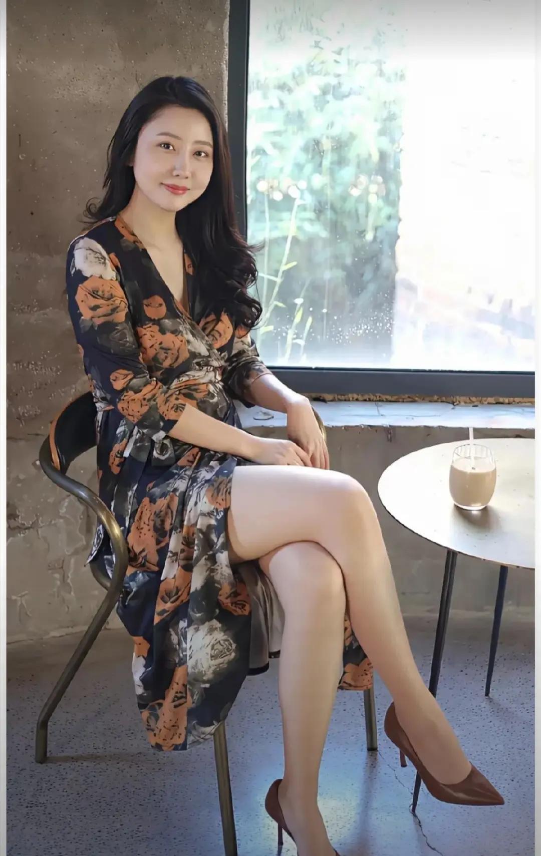 漂亮的美女坐在窗边，喝着咖啡。