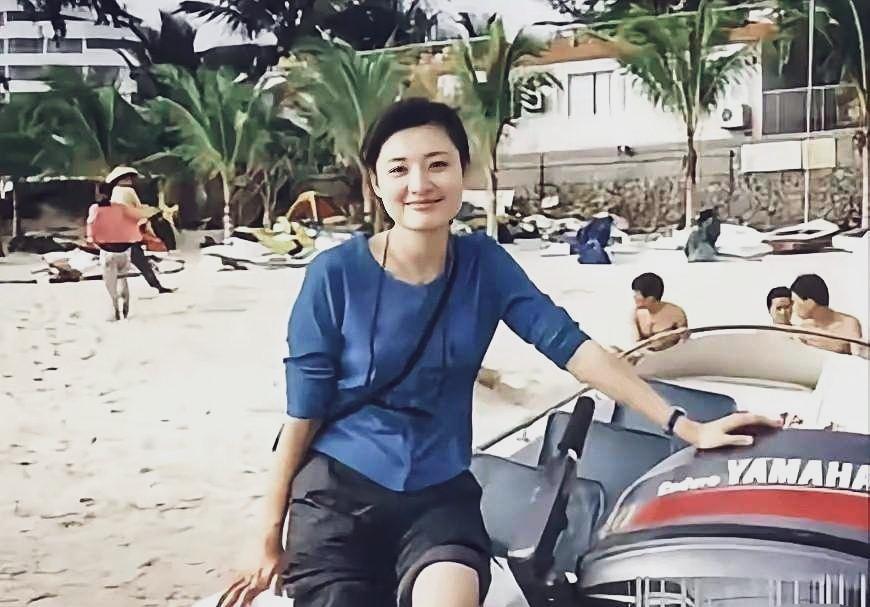 周涛一副大学生的模样，皮肤白皙光滑，蓝色的上衣配上黑色的裤子，裤腿挽起，坐在沙滩