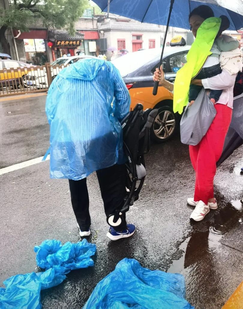北京街头，大雨中，外国友人一家四口，拒绝了一辆停在他们身边，打算主动帮助他们的出