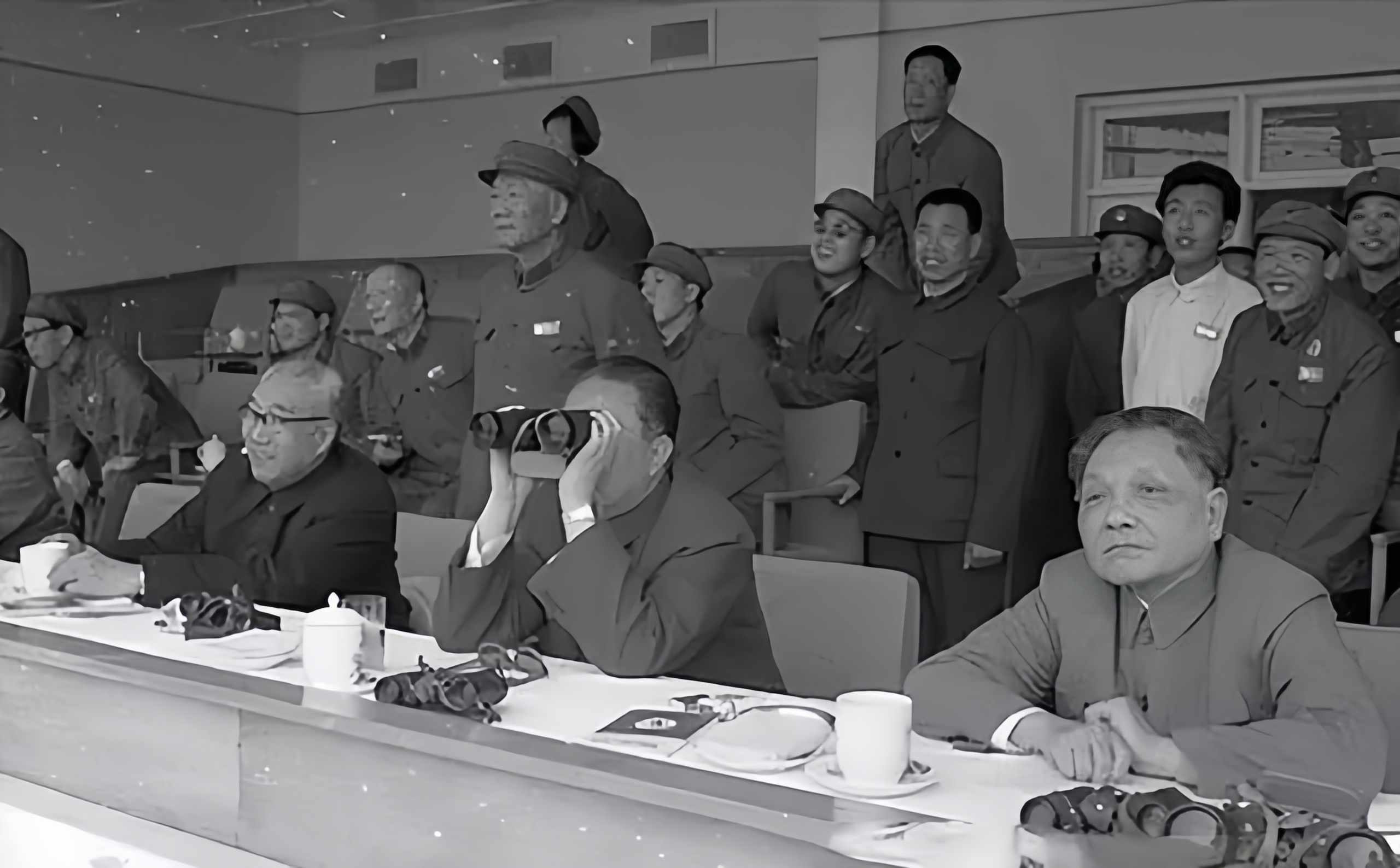 这是军委首长观看全军演习的场景。前排右一是军委副主席邓小平，前排左一戴眼镜的是徐