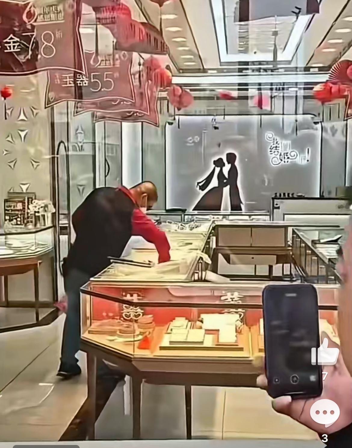 上海周浦一男子抢劫金店，人还没走出金店就被抓。透过玻璃窗，一堆人拿着手机拍照围观