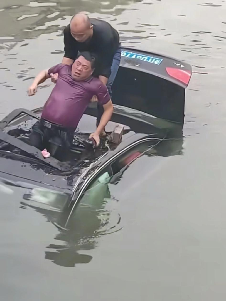 小车为避让骑车闯红灯的女子不慎坠入河中危急时刻一男子带着一块砖头跳入水中，用