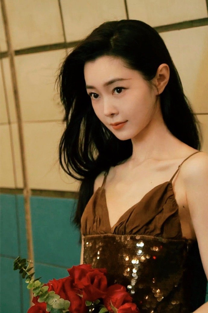 宋轶优雅的长发轻垂肩头，一袭吊带裙衬托出柔美的身姿。她手捧鲜花，却比花更为惊艳