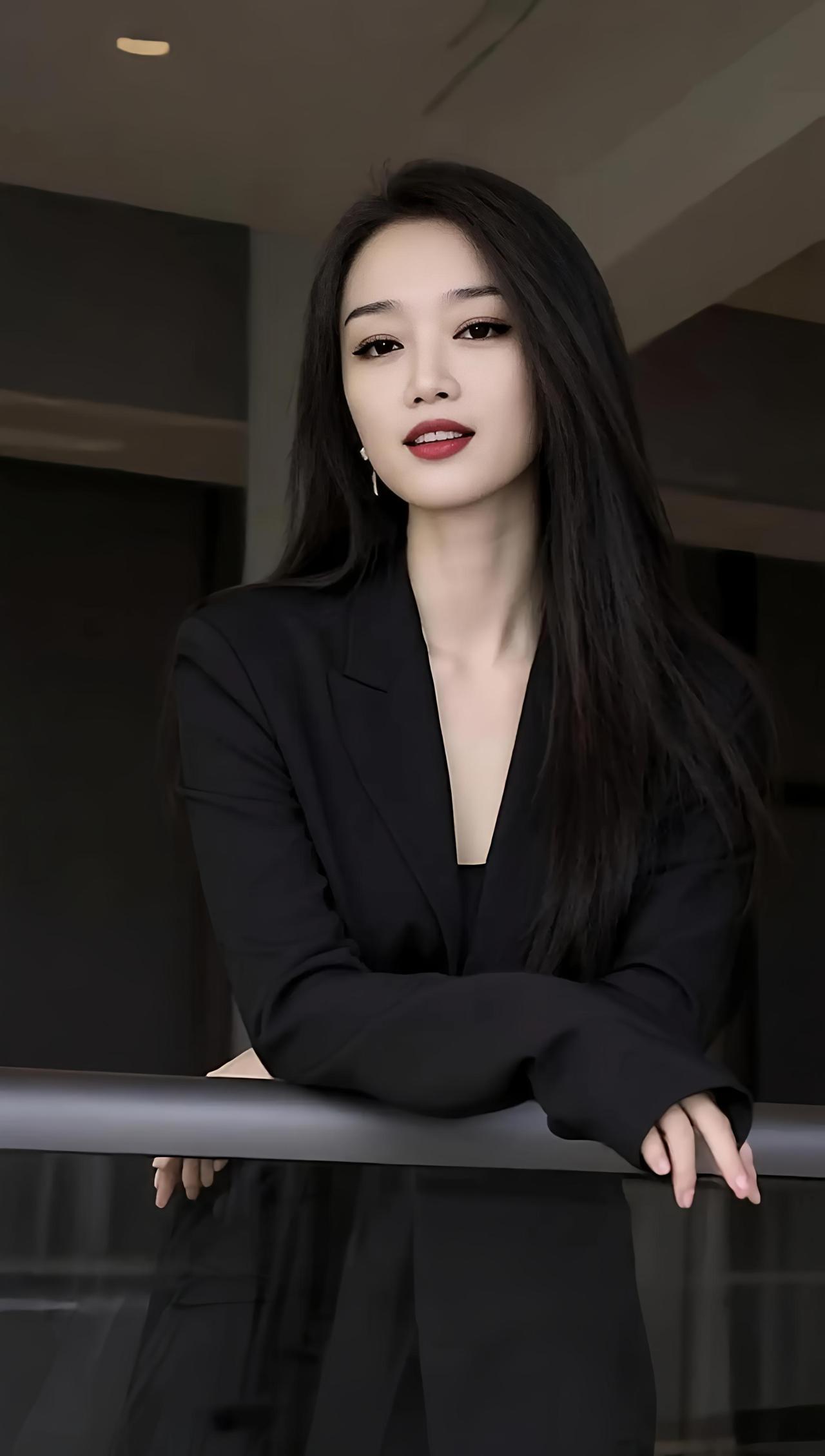 这位美女穿着黑色西装，靠在栏杆上。气质西装女神