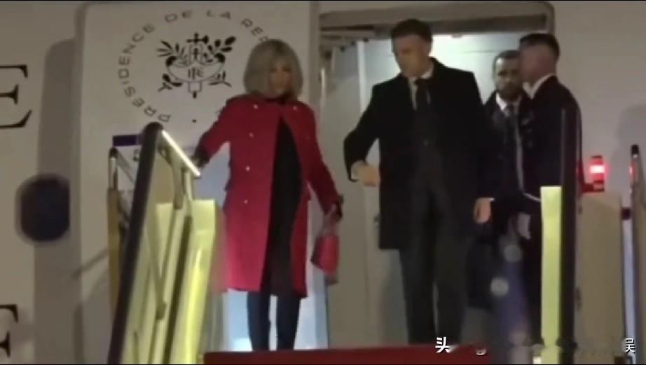 法国总统马克龙夫妇抵达北京首都国际机场，夫妻俩手挽着手走下飞机舷梯，画面甜蜜又恩
