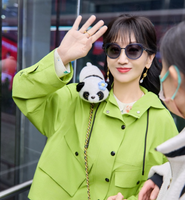 赵雅芝里面穿白色打底衫外面套着绿色的宽松外套，两件衣服叠穿的效果很不错。她下