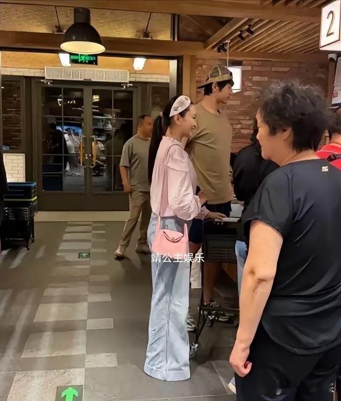 金莎和老公孙丞潇超市购物被偶遇，她扎着低马尾，身穿粉色衬衫配阔腿裤，头戴粉色发箍