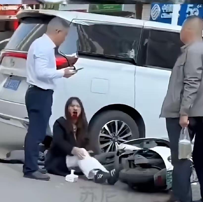 姑娘骑电动车被一辆白商务车撞了。门牙直接磕掉，血止不住地流，疼得说不出话，只能哭