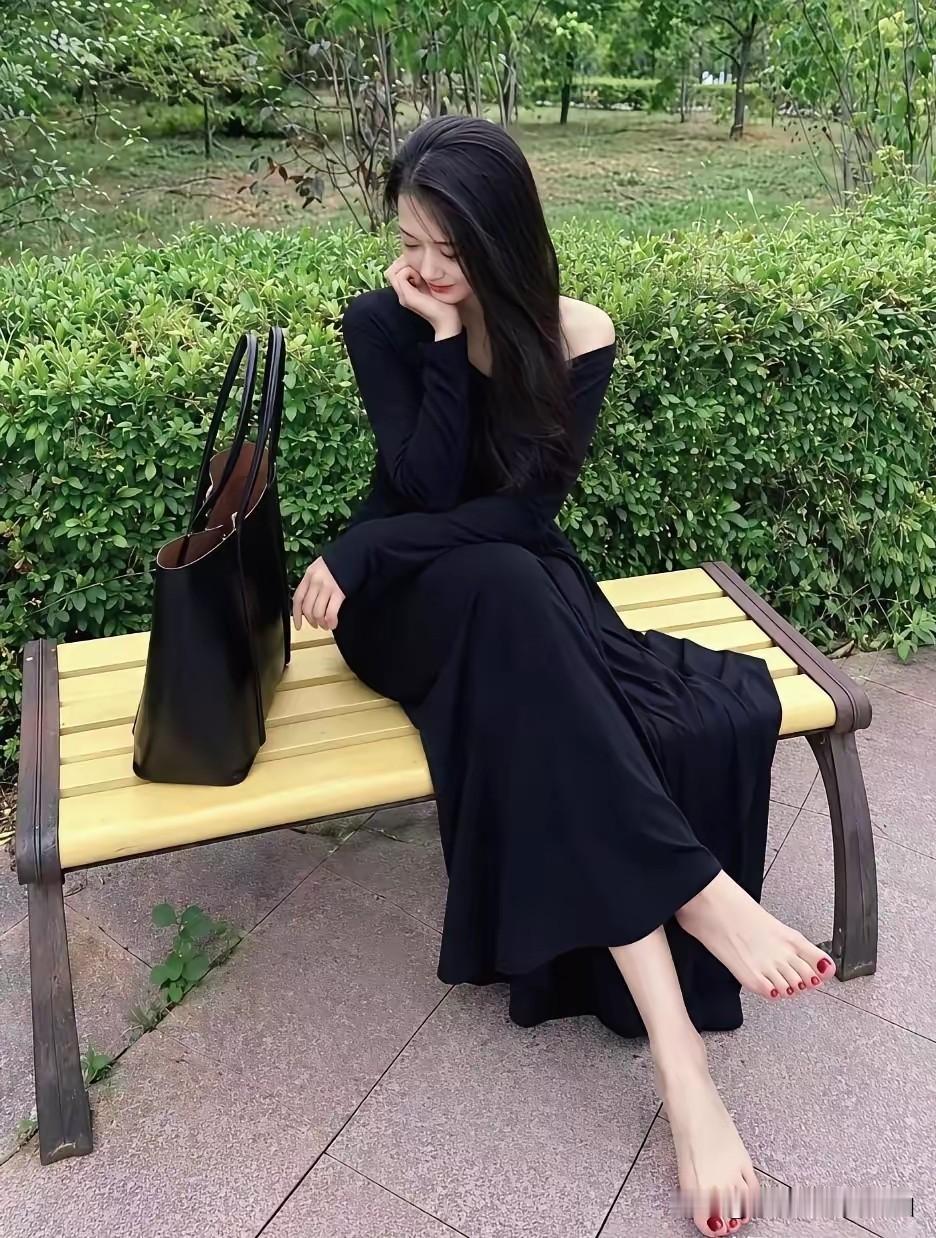 一身垂坠感黑裙衬得气质沉静又温柔，露出的足部肌肤白皙细腻，酒红色的美甲添了几分精