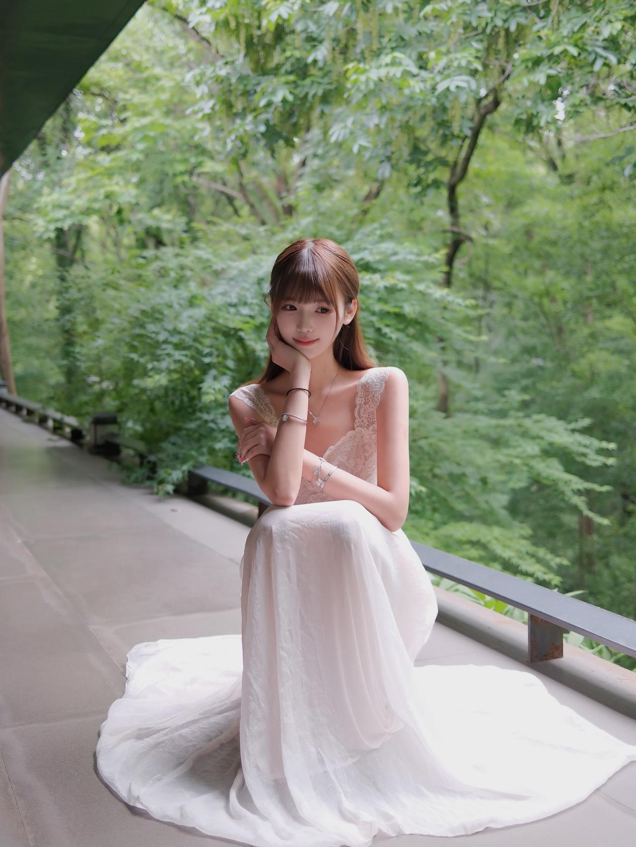 优雅白裙少女，静坐绿意盎然中，感受自然之美。