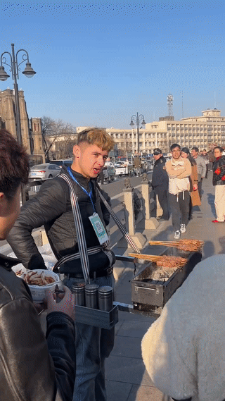 这是天津街头卖流动烤串的新疆小伙。看起来他的生意还挺不错的。不仔细看，还以为