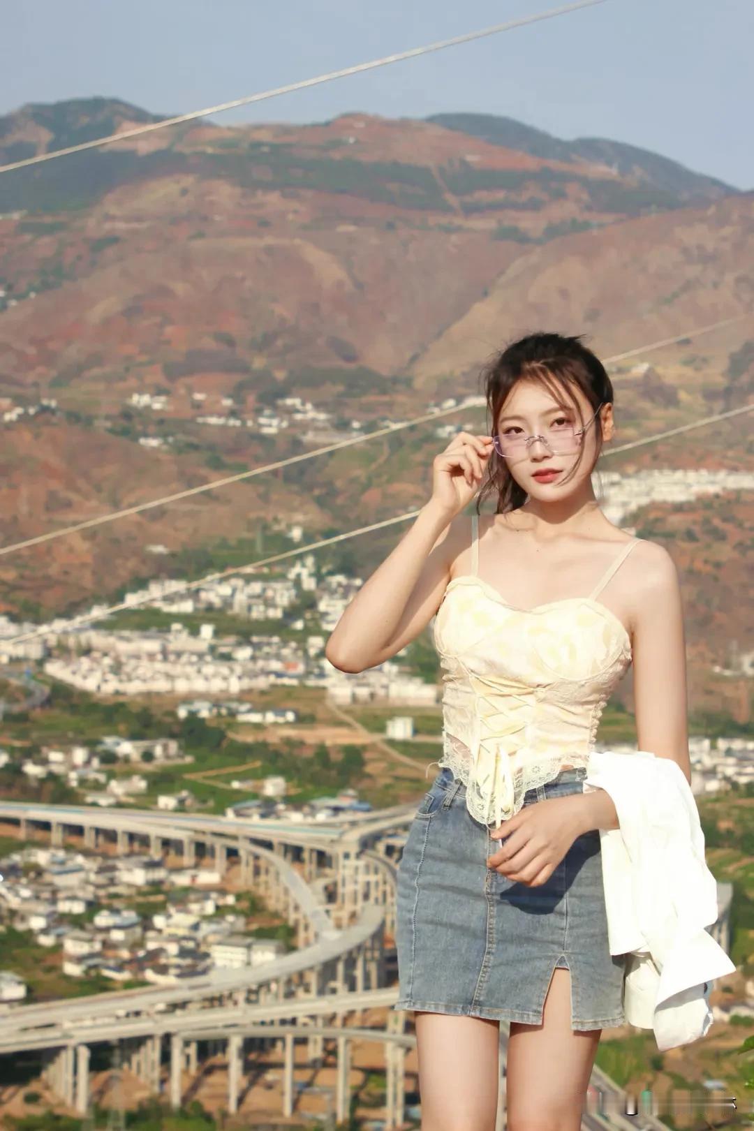 在山顶的少女云雾缭绕，风拂发梢，她站在峰巅，目光越过群山，是征