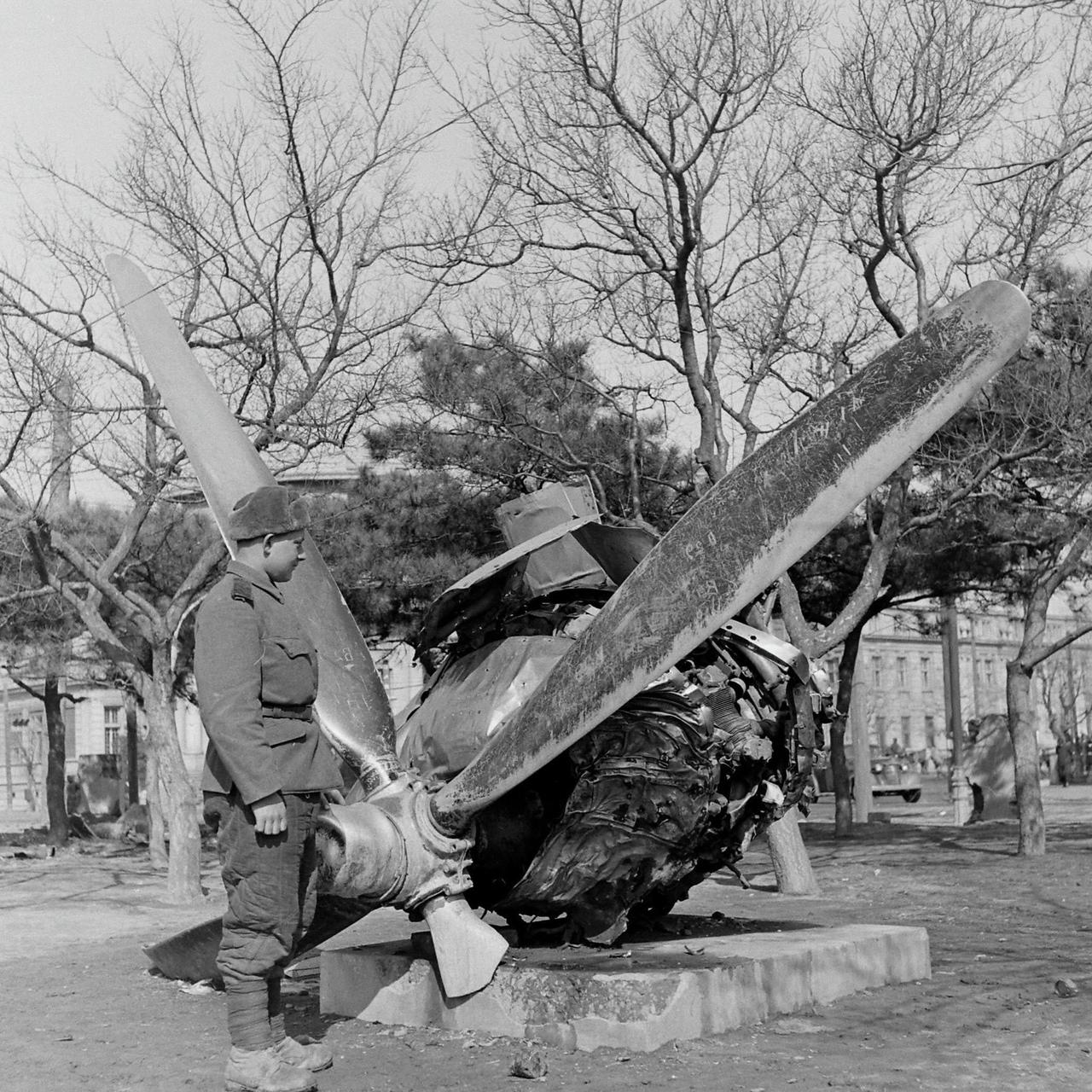 1946年3月，中国沈阳城内一处公园里，一名苏联红军士兵站在一台发动机残骸前细细