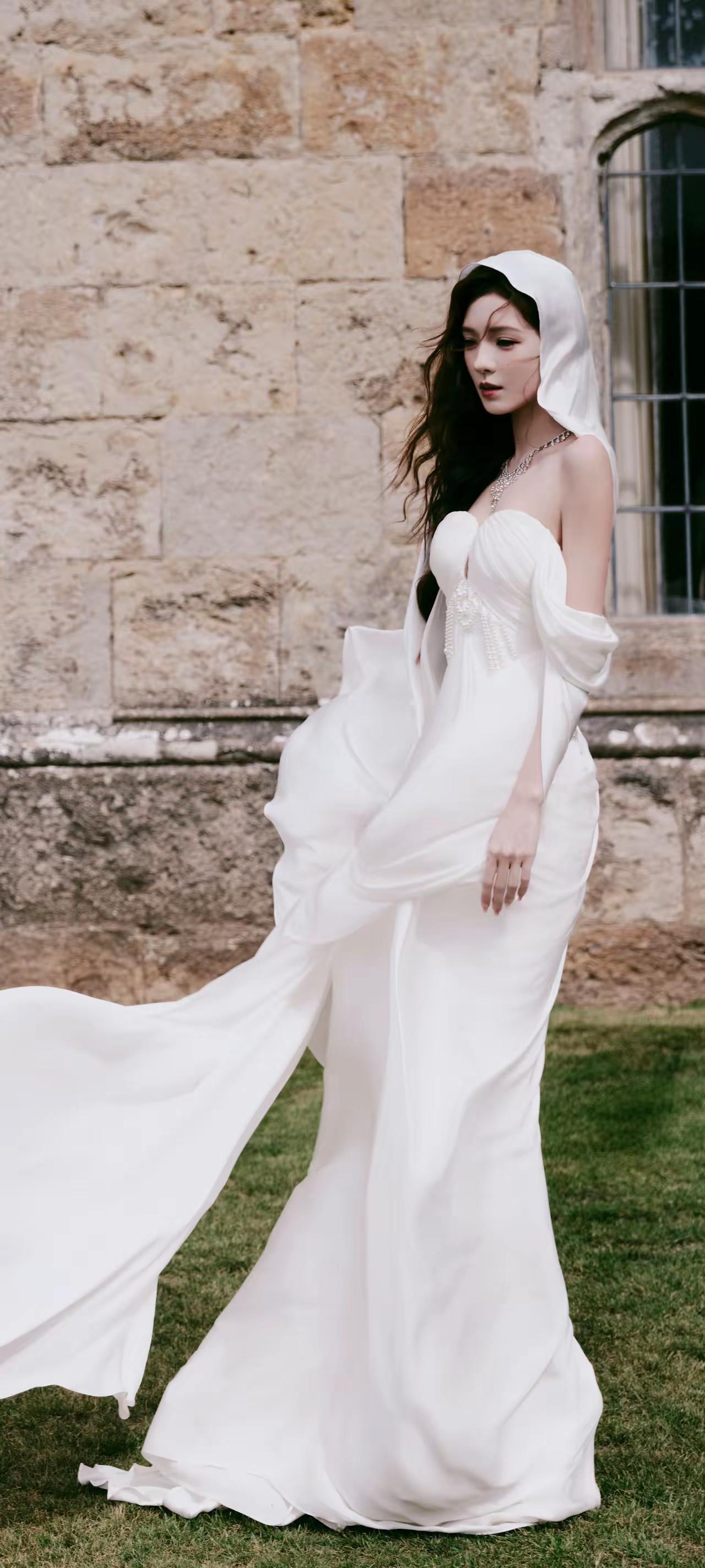 张予曦，白纱漫过肩头，风拂过古堡与窗棂。珍珠缀起浪漫，纱幔裹住温柔，每一缕卷发都