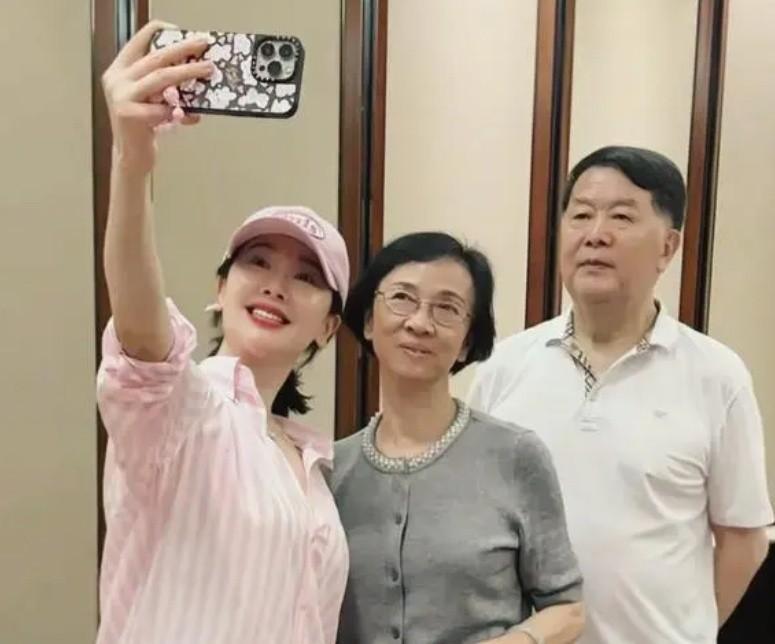 左小青回老家看望爸妈，一家三口合影好温馨！49岁穿粉色衬衫配棒球帽，温婉娴静显活