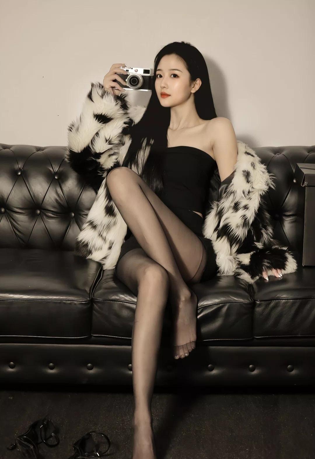 黑白皮草披肩裹着冷艳格调，黑抹胸配黑丝勾勒出曼妙线条，手持相机的瞬间，将复古与摩