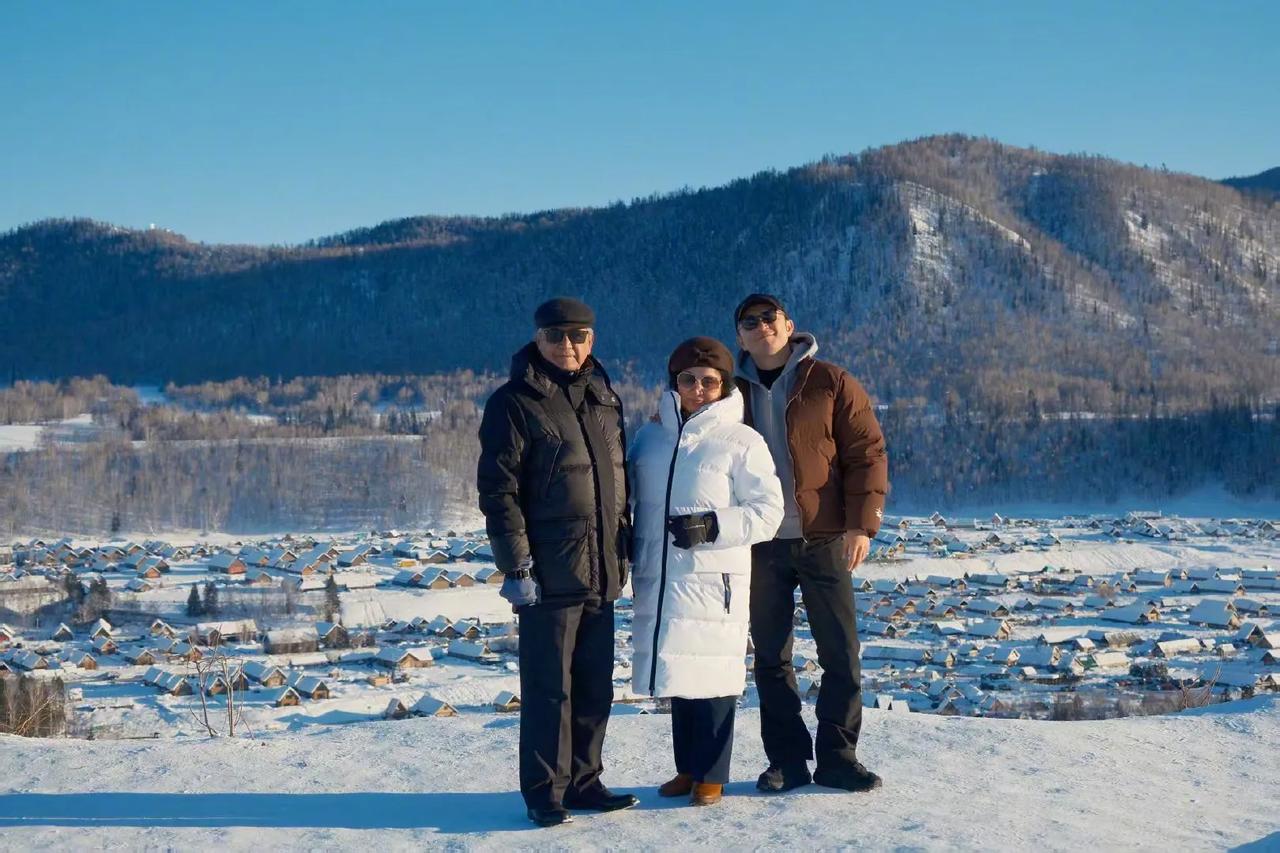 尼格买提和父母在雪山合照，小尼笑容灿烂，爸爸穿黑色羽绒服，沉稳帅气，妈妈穿白色羽