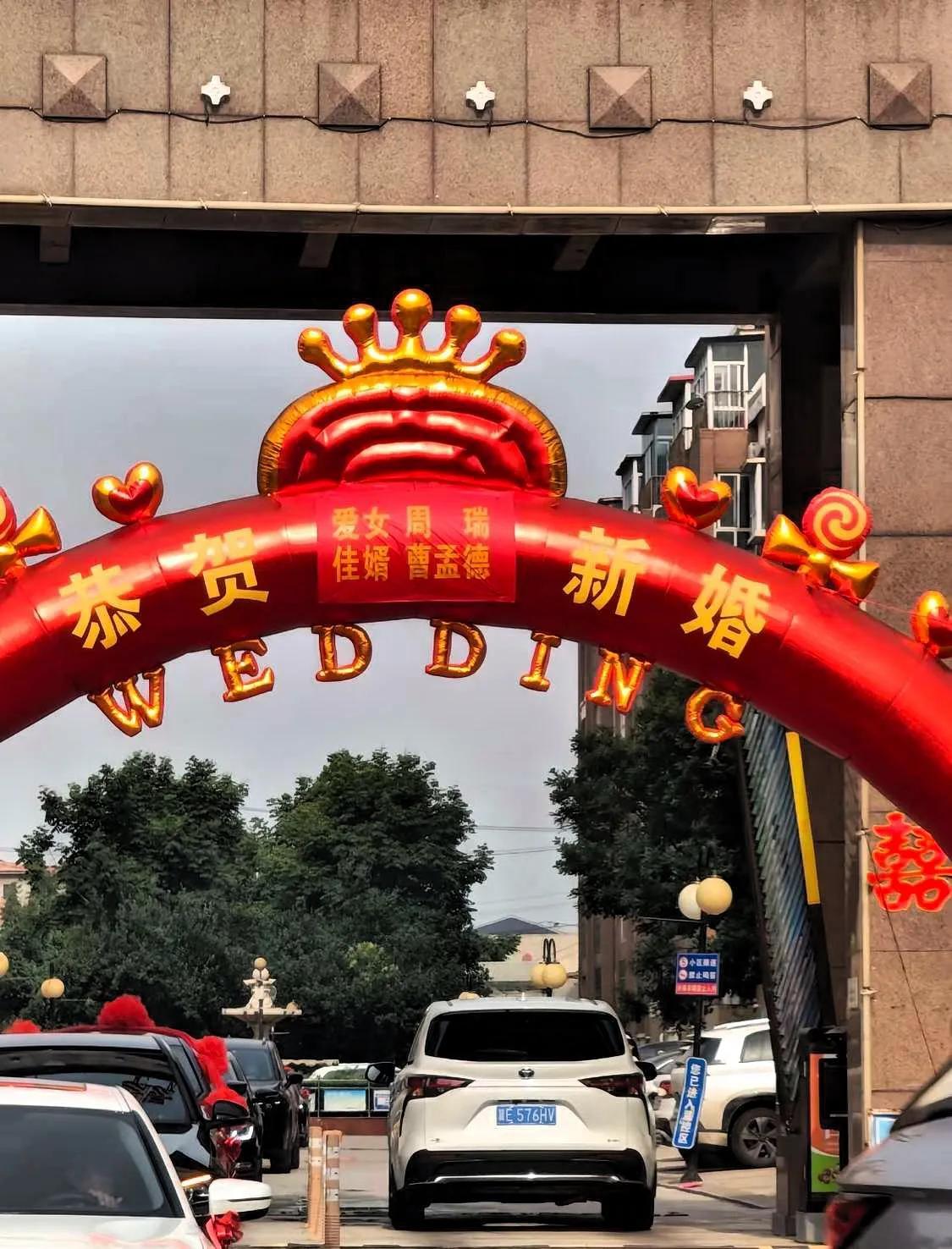 小区门口立着喜庆的结婚充气拱门，上面写着新人名字。我盯着"佳婿"那一行看了半天