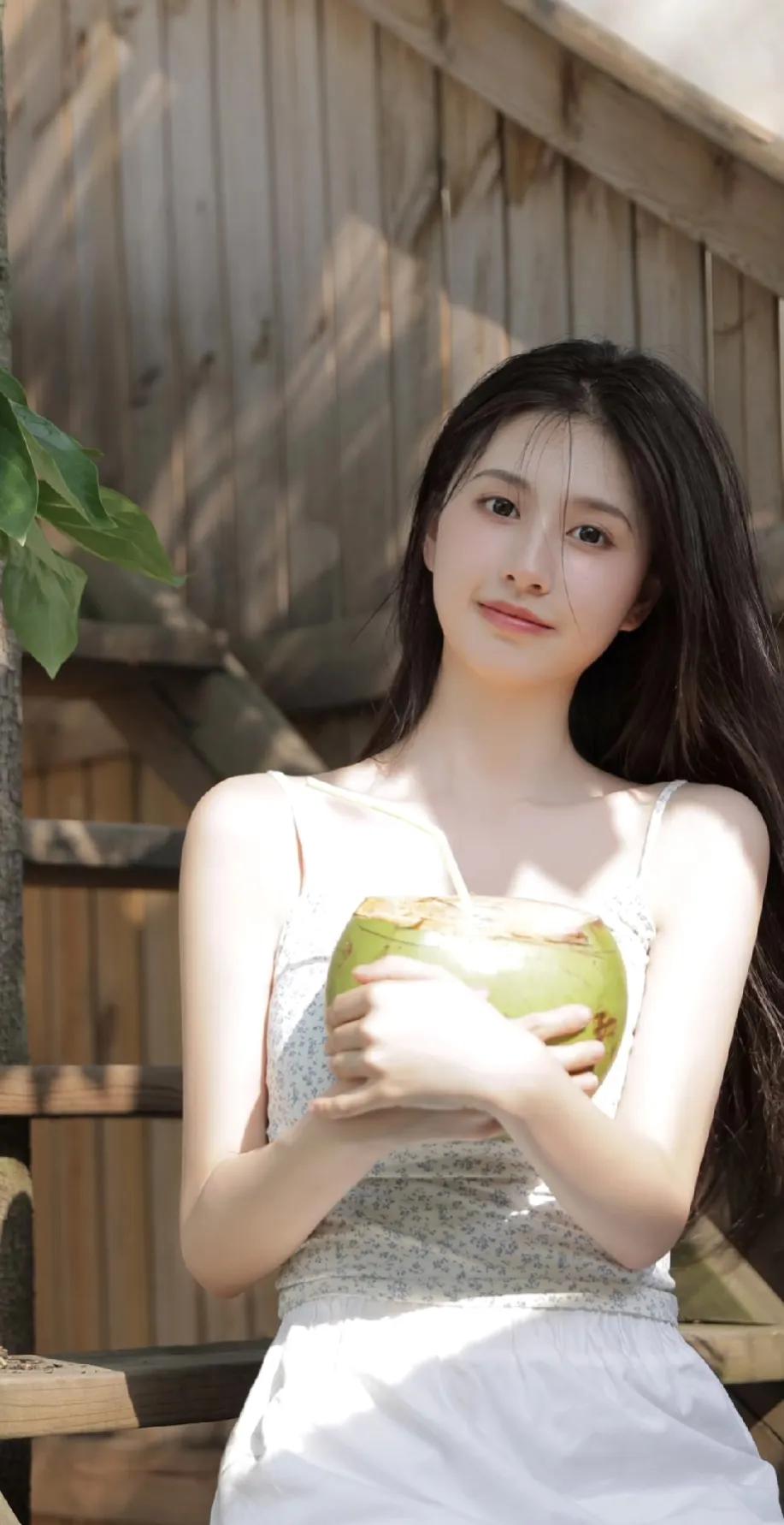 一个美女抱个椰子喝椰汁