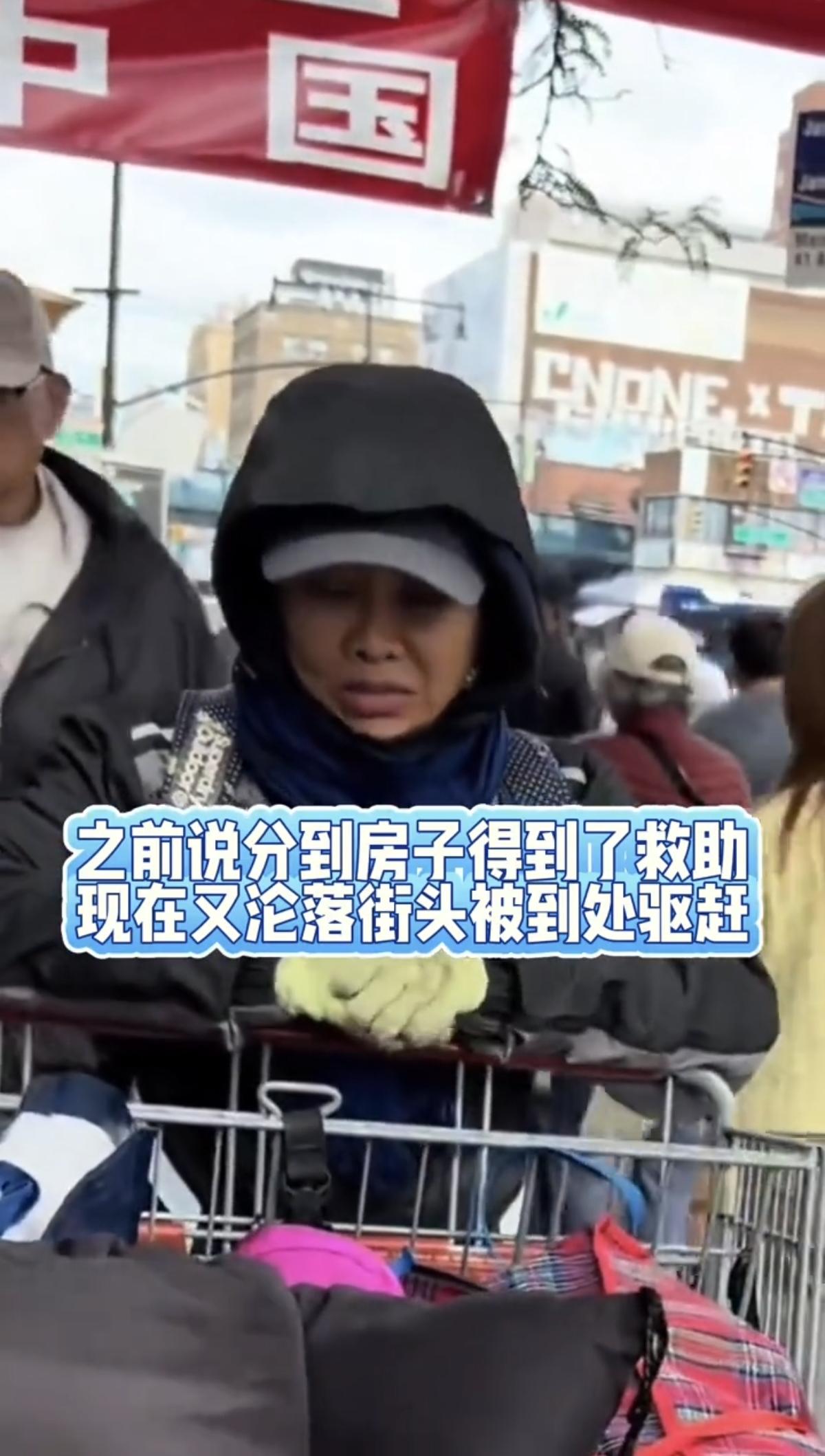 纽约法拉盛的街头，一位中年女人孤零零站在路边，身前一个破旧的购物手推车，装着她全