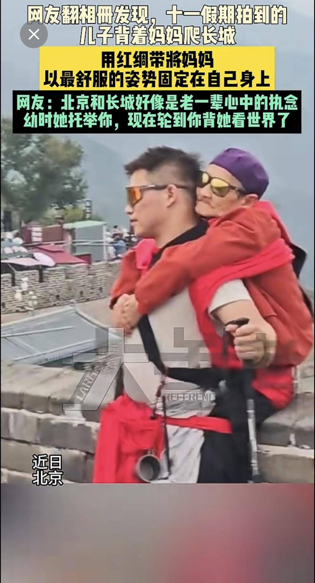 近日北京网友翻相册发现，十一假期拍到的儿子背着妈妈爬长城。用红绸带将妈妈以最舒