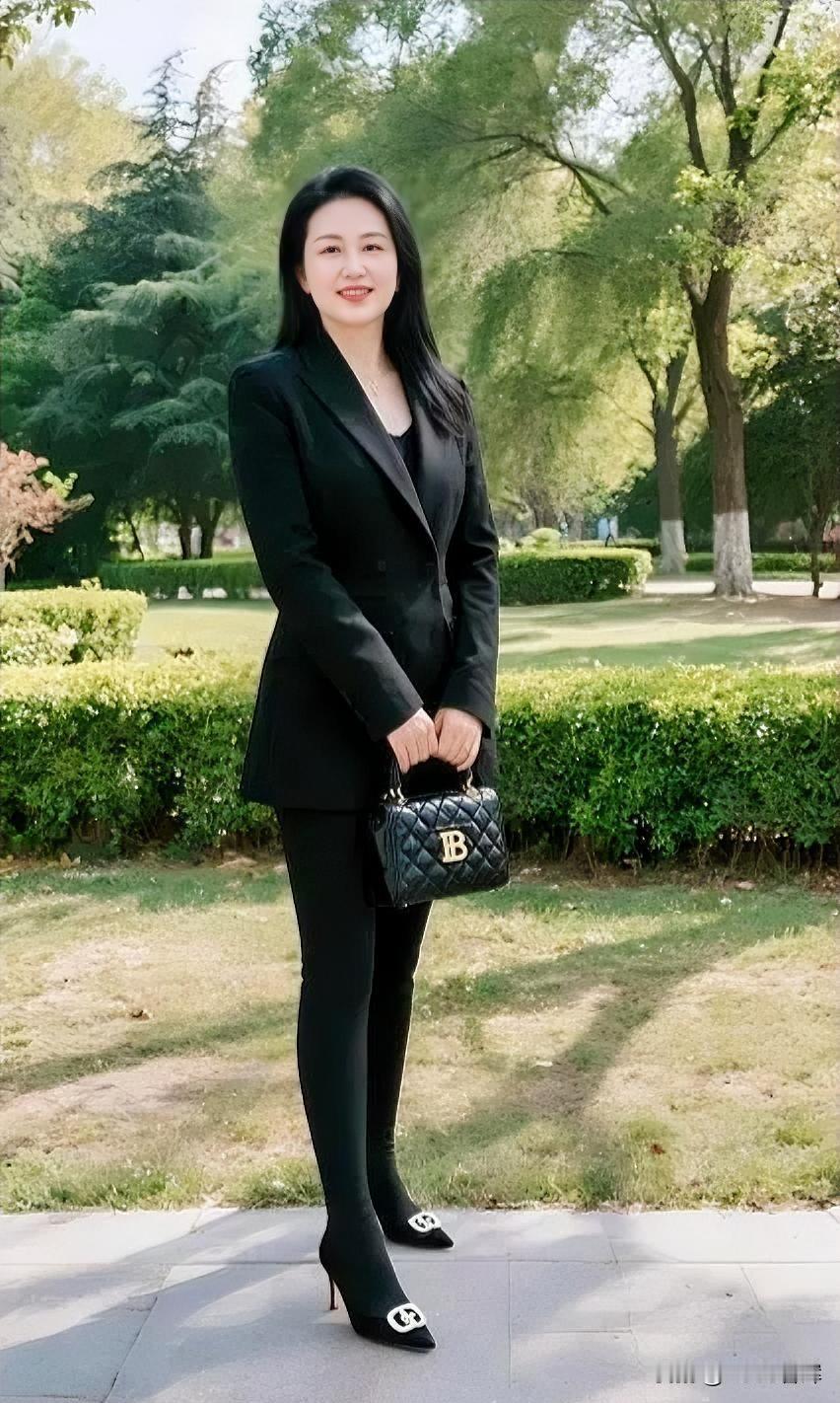 黑西装配绿意，手提包精致。站在阳光里，笑容自信，自在从容。