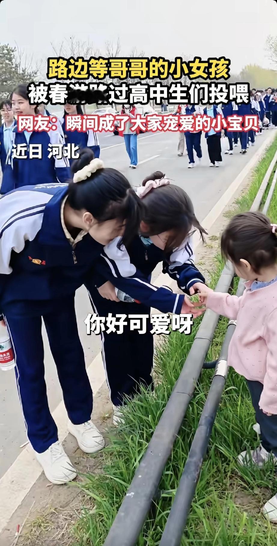 河北一个小女孩，站在路边等哥哥。一群春游路过的高中生看见了，小姑娘扎着两个小