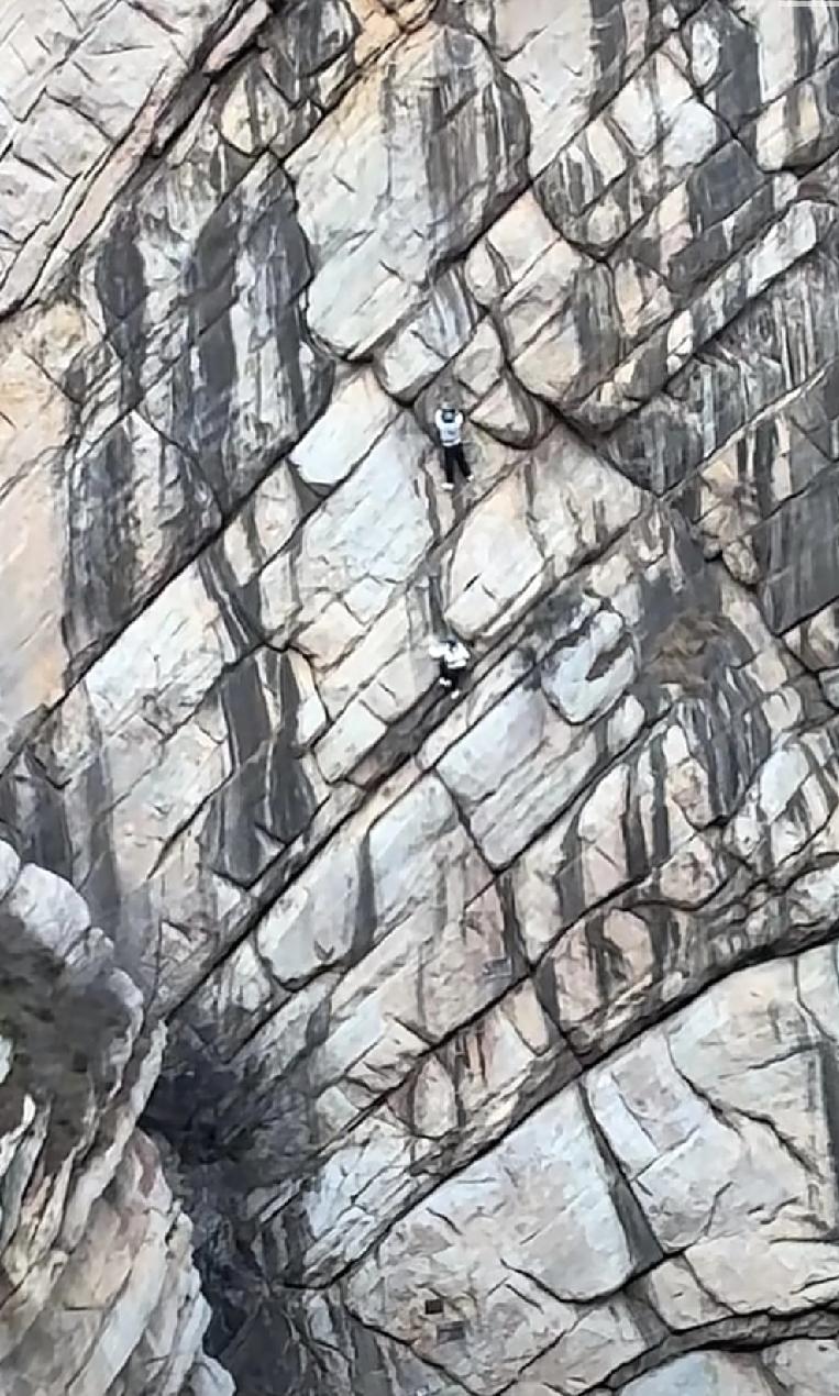 河南郑州最有名的景区内很多游客发现两个人在几乎垂直的山体上进行攀登而且攀登过