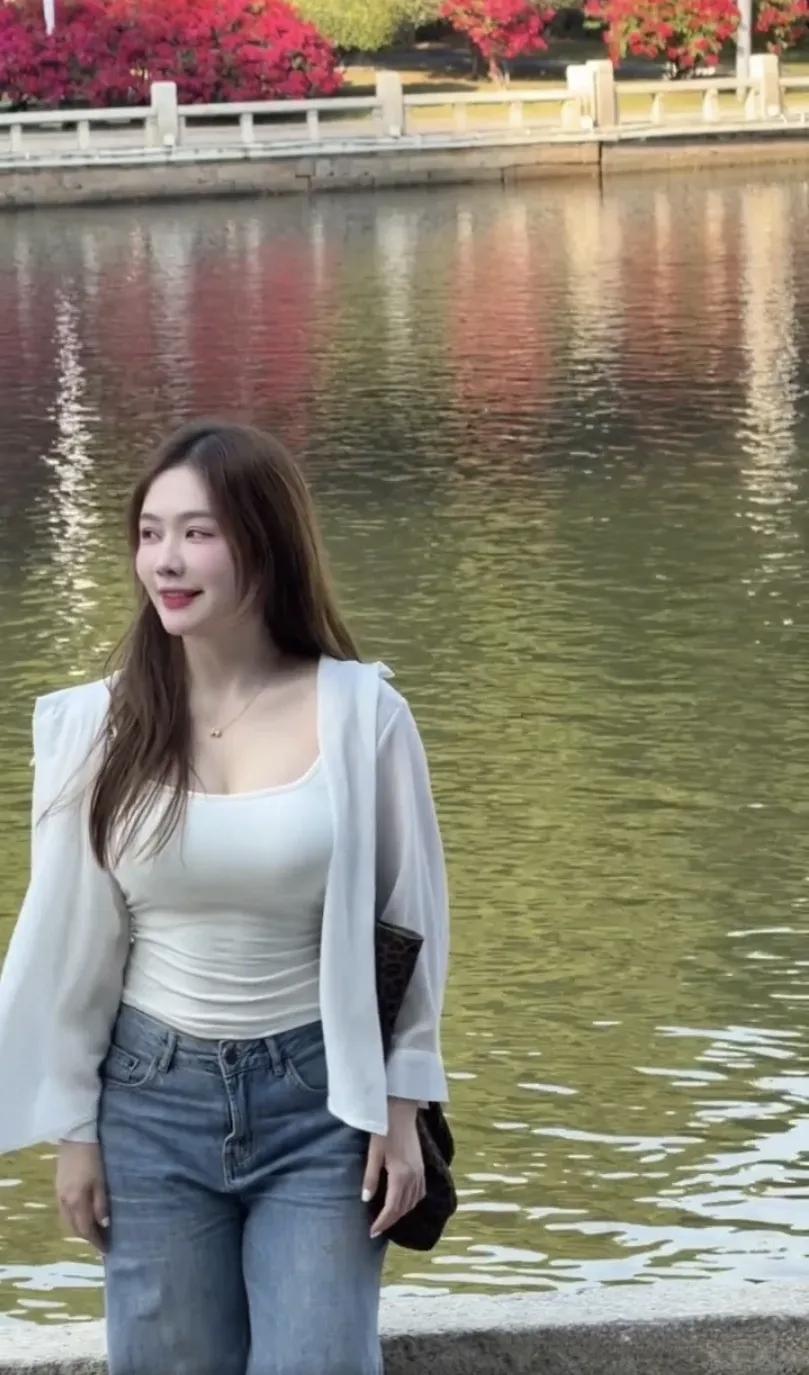 女孩站在湖边，微笑看远方。