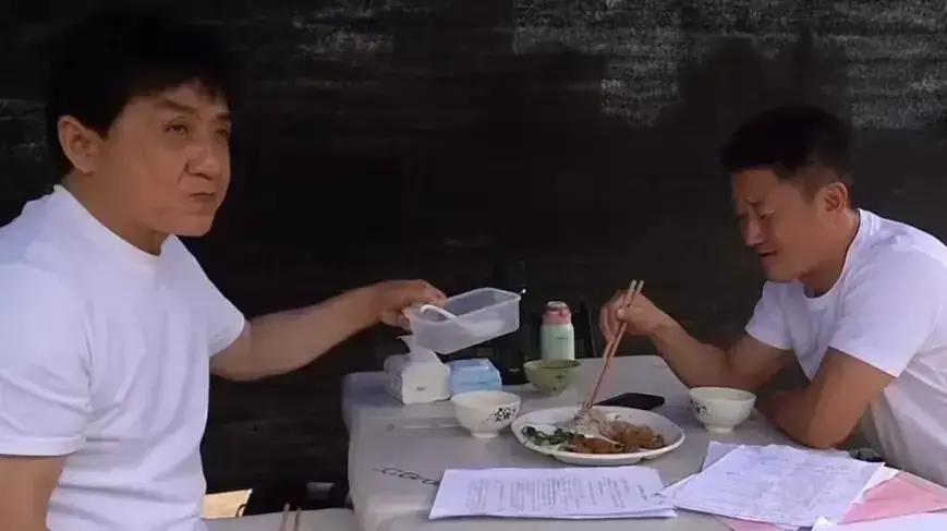 片场蹲着吃盒饭，成龙把掉膝盖的饭粒捡起来塞嘴里，吴京扒完白菜炒肉，还喊场务“再来