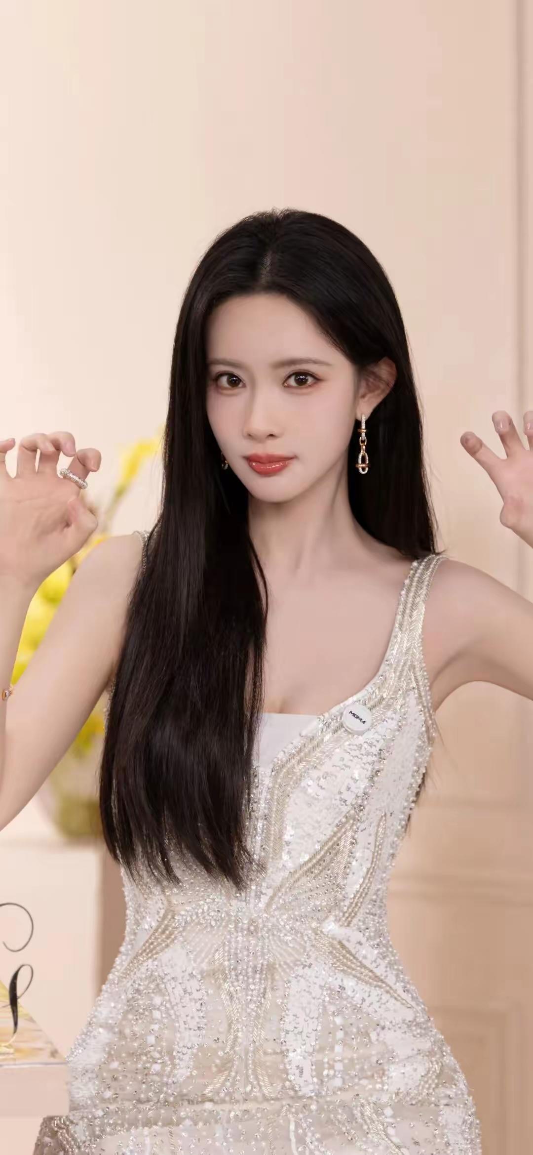 孟子义，银白亮片缀满裙身，如揉碎的星光落满肩头。黑长直发温柔垂落，灵动俏皮的手势