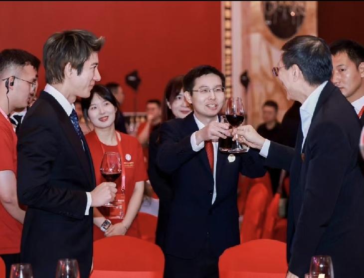 手拿酒杯的王力宏看着敬酒的王兴兴，就像粉丝看偶像；与人合影的王兴兴表情严肃，其