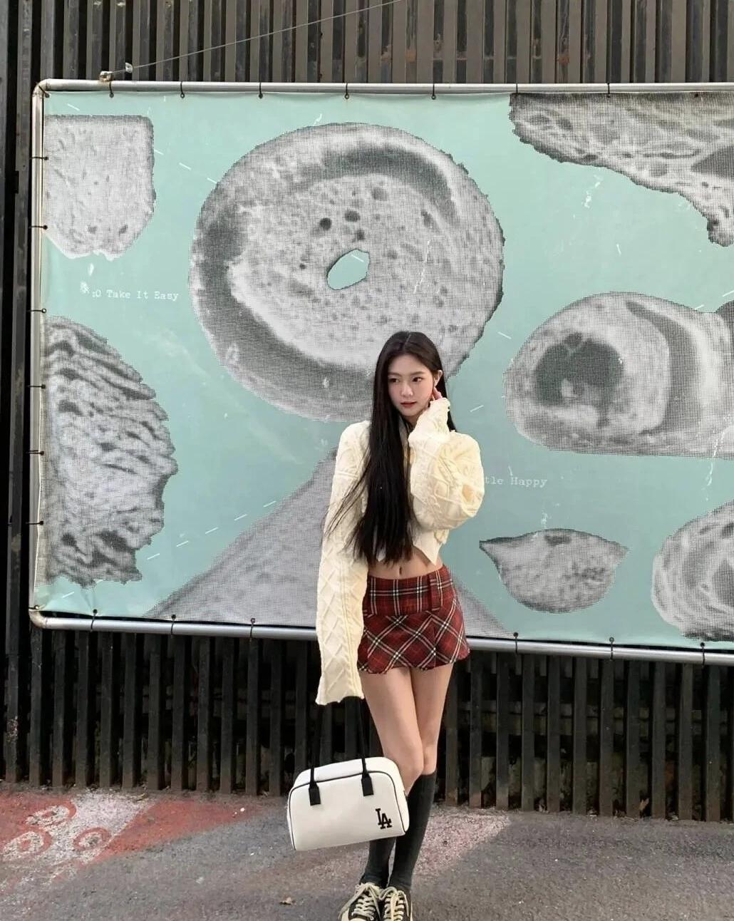 薄荷绿背景墙撞出复古趣味，杏色开衫搭红格短裙甜酷拉满，在街头和可爱的涂鸦海报同框