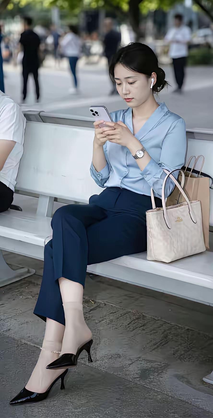 穿得职业，坐在长椅上玩手机。