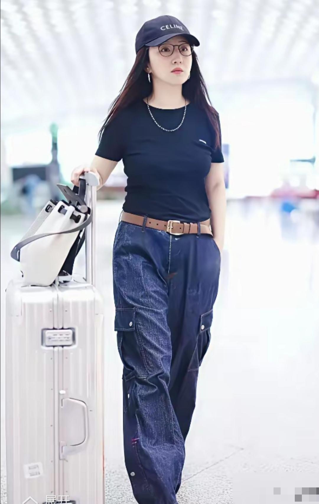 53岁杨钰莹出现在机场，黑T恤配工装裤，外加一顶休闲帽，整体穿着随性大方，又不失