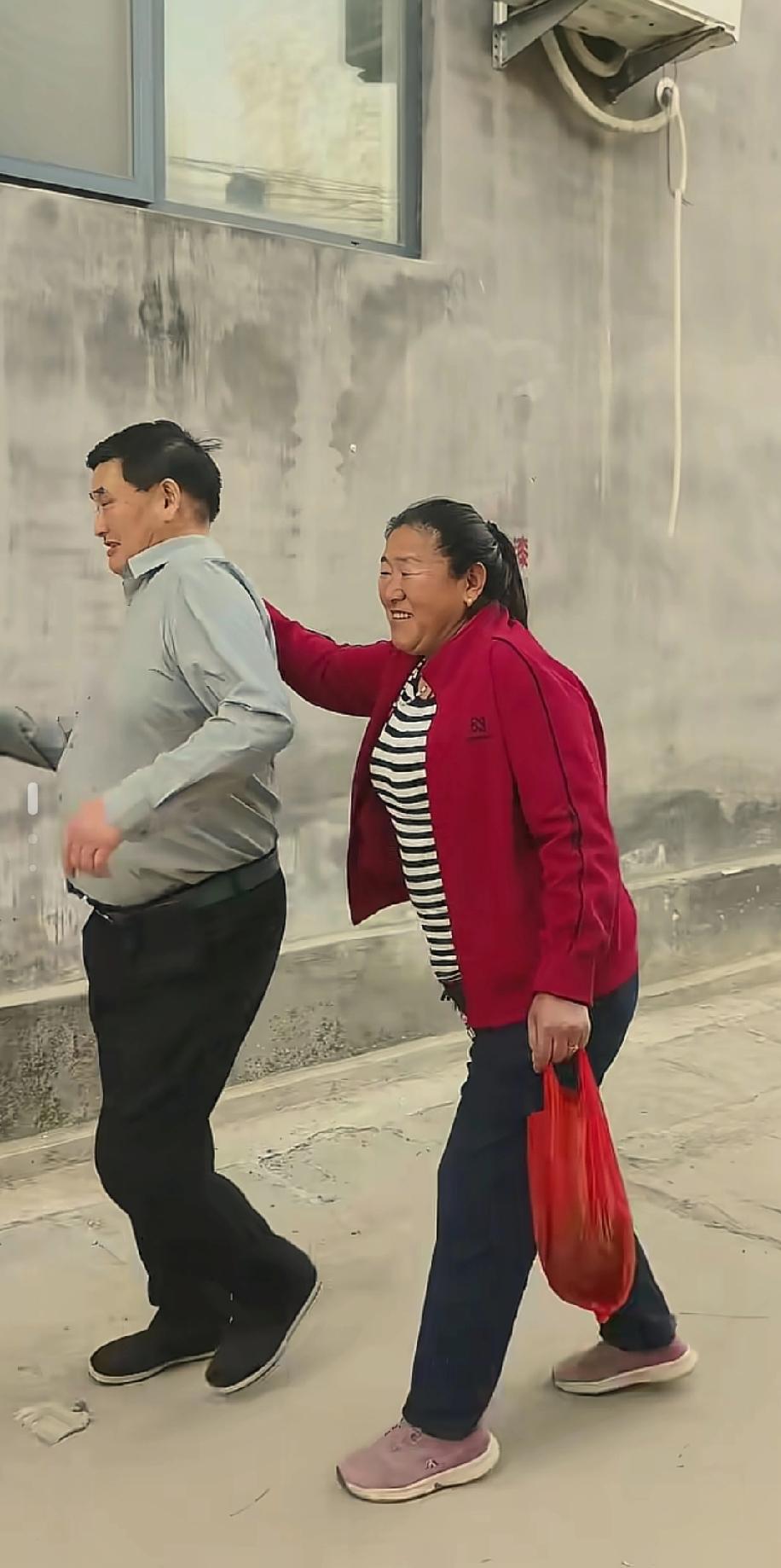 大衣哥和大衣嫂笑容满面地外出归来，当镜头对准他们的那一刻，大衣嫂有意地将手搭在大