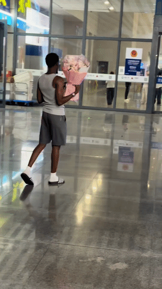 浙江台州。有当地网友在火车站看到一名黑人男子手捧一束鲜花站在出站口准备迎接他的