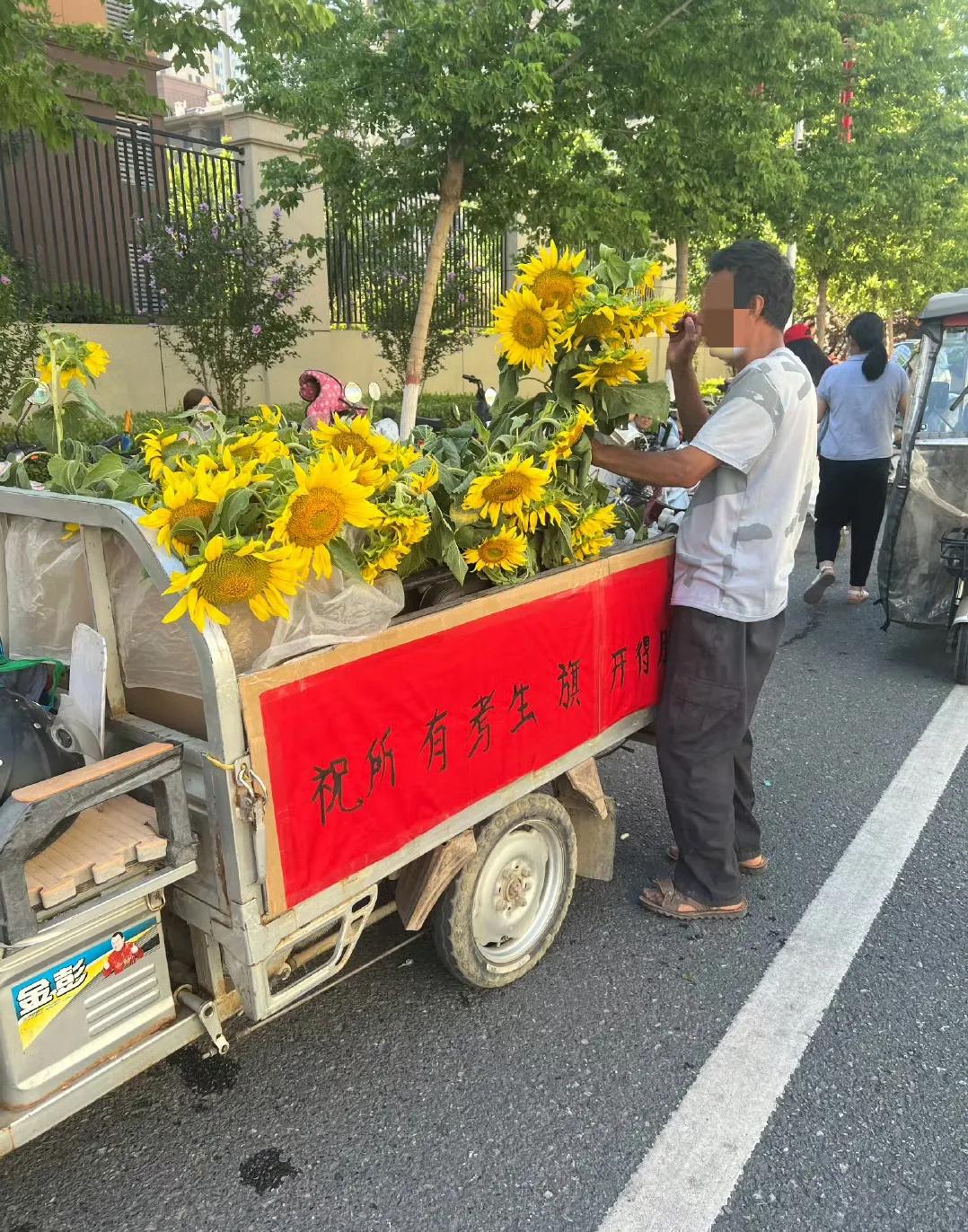 6月21日，河北中考第一天。邯郸市下属县某考点外，一个开着电动三轮车卖向日葵的6