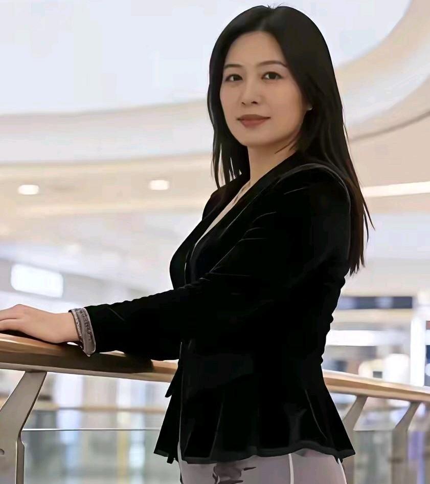 穿搭很有自己的风格，上身是有质感的黑丝绒，下身穿穿着水墨画的花裙，依偎商场护栏而