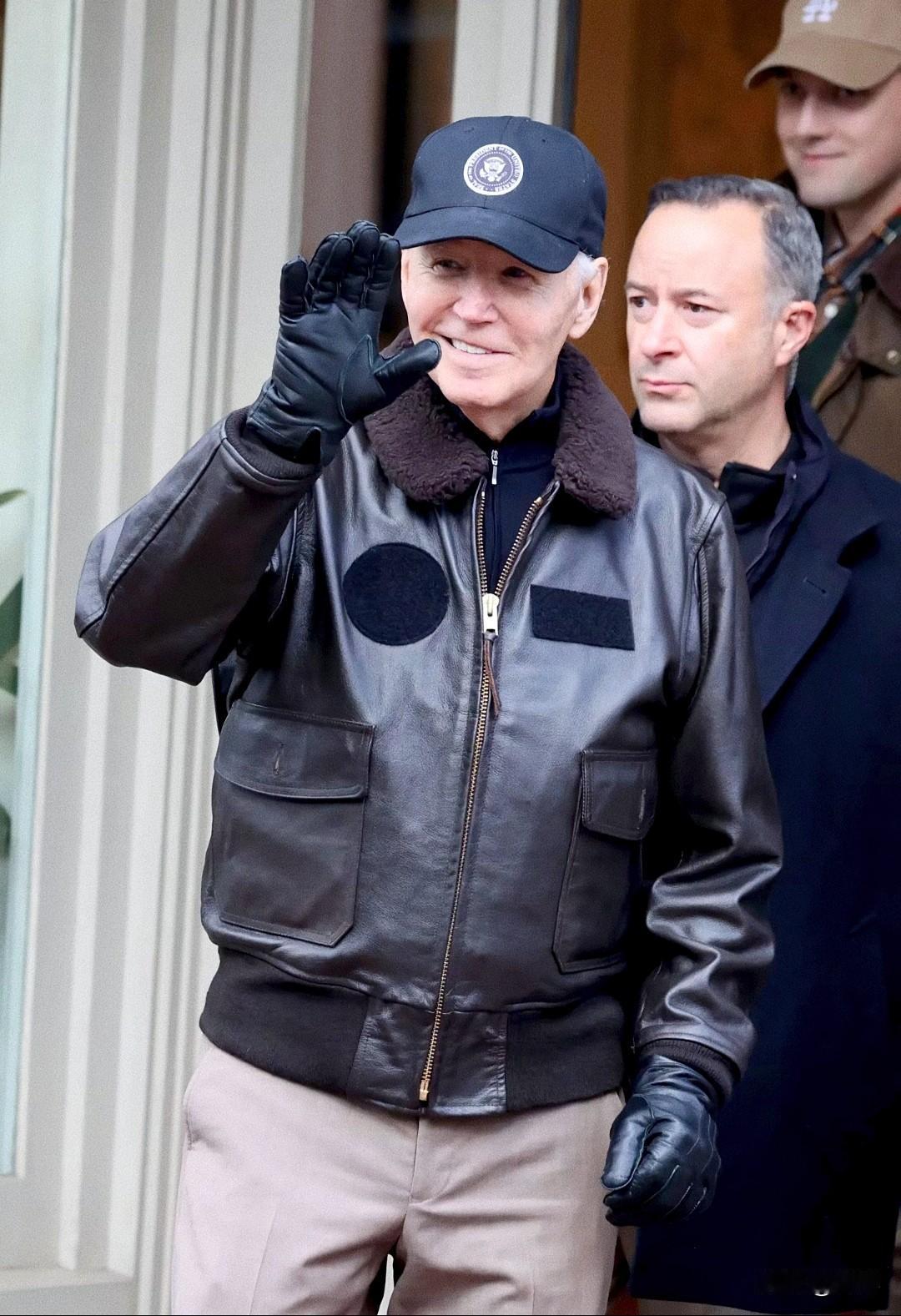 拜登.穿着皮夹克戴着皮手套像认出他的人招手。