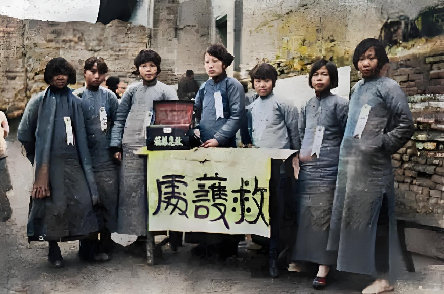 照片中几位身着传统服饰的女性站在一起，她们身前的桌子上，有写着“救护处”的横幅，