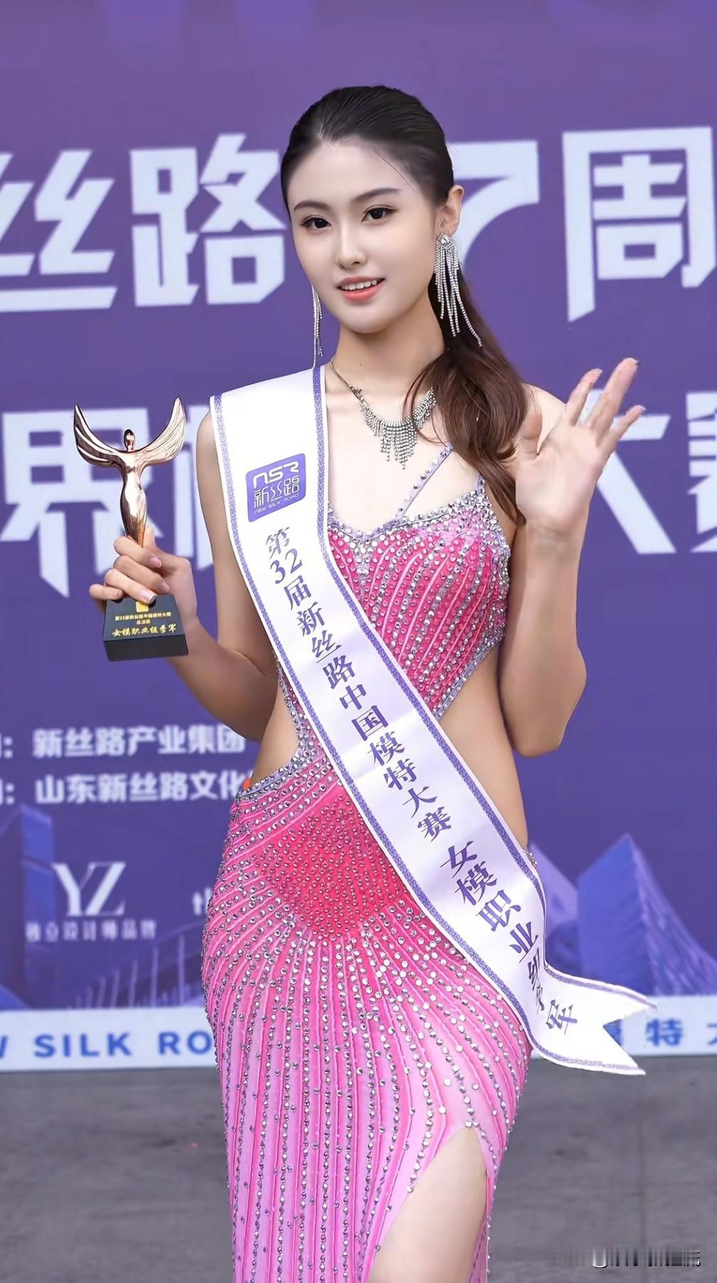 第32新丝路模特大赛16号出场选手虎双艺，手持奖杯自信从容地迈向舞台中央，亲切地