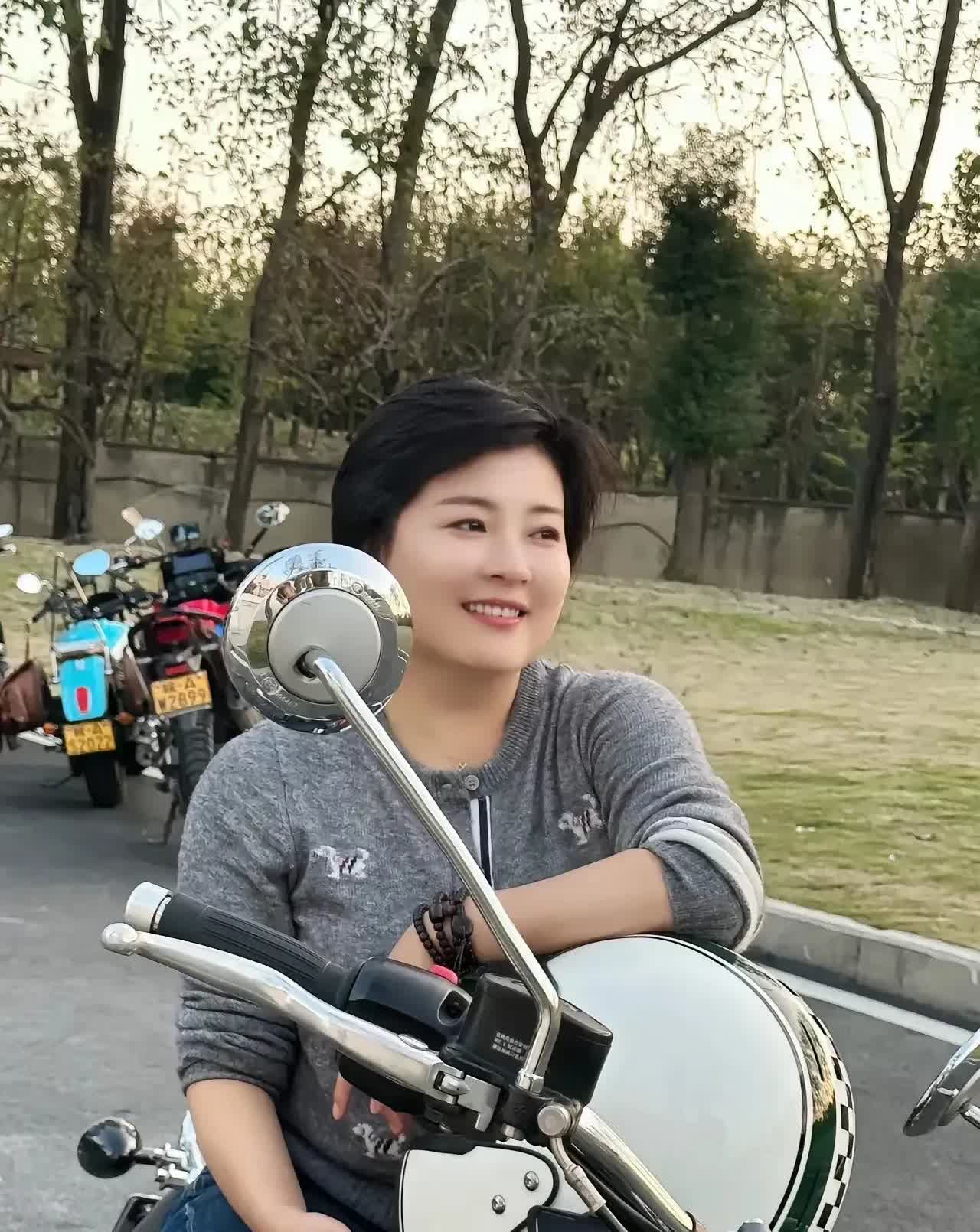 夕阳余晖洒落，她与心爱的凯旋摩托相伴。简约灰衣搭配牛仔裤，随性又自在。或倚靠车把