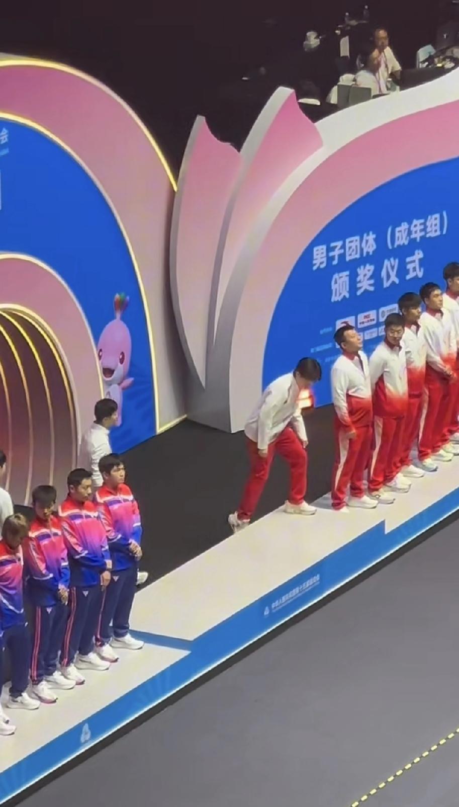 大头在龙队面前真乖。男团颁奖仪式中，出现一个有趣的现象。有大头带队，龙队紧随其