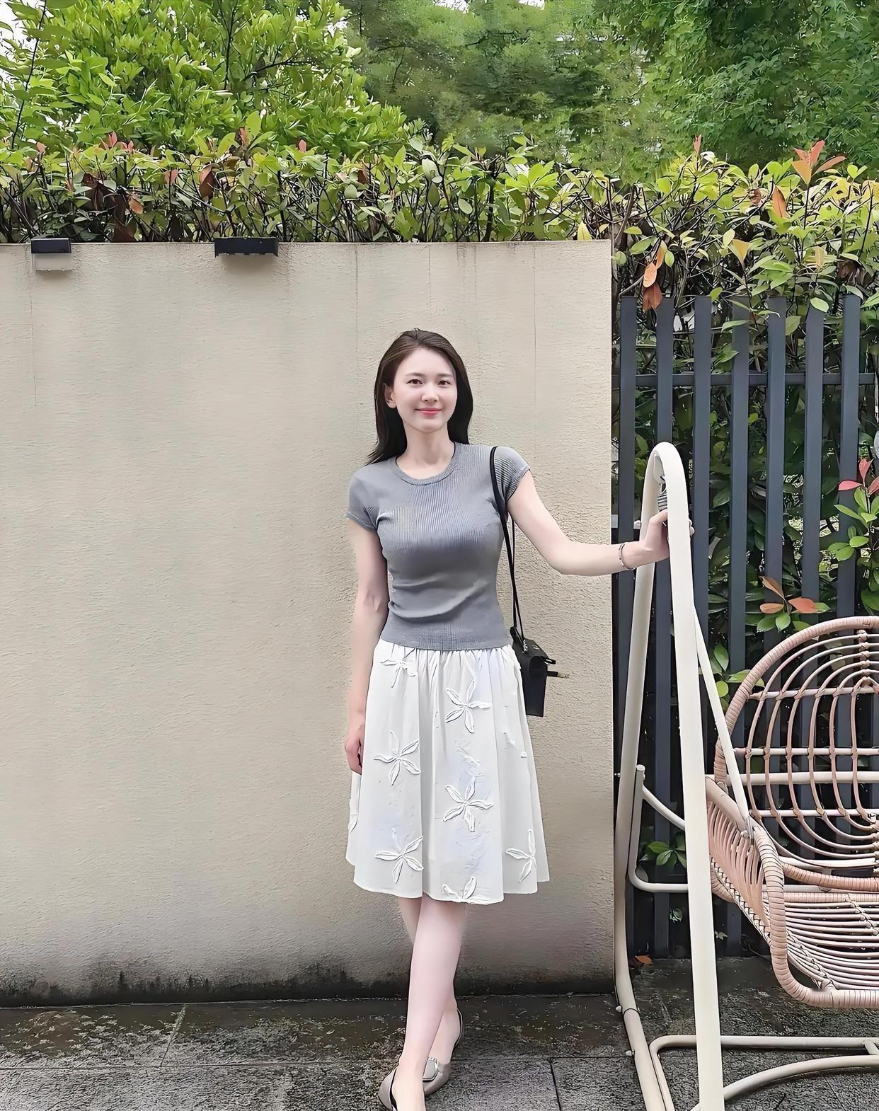 绿意环绕，墙前小立，灰衫白裙，清新如你。裙上花朵，悄然绽放，浅笑盈盈