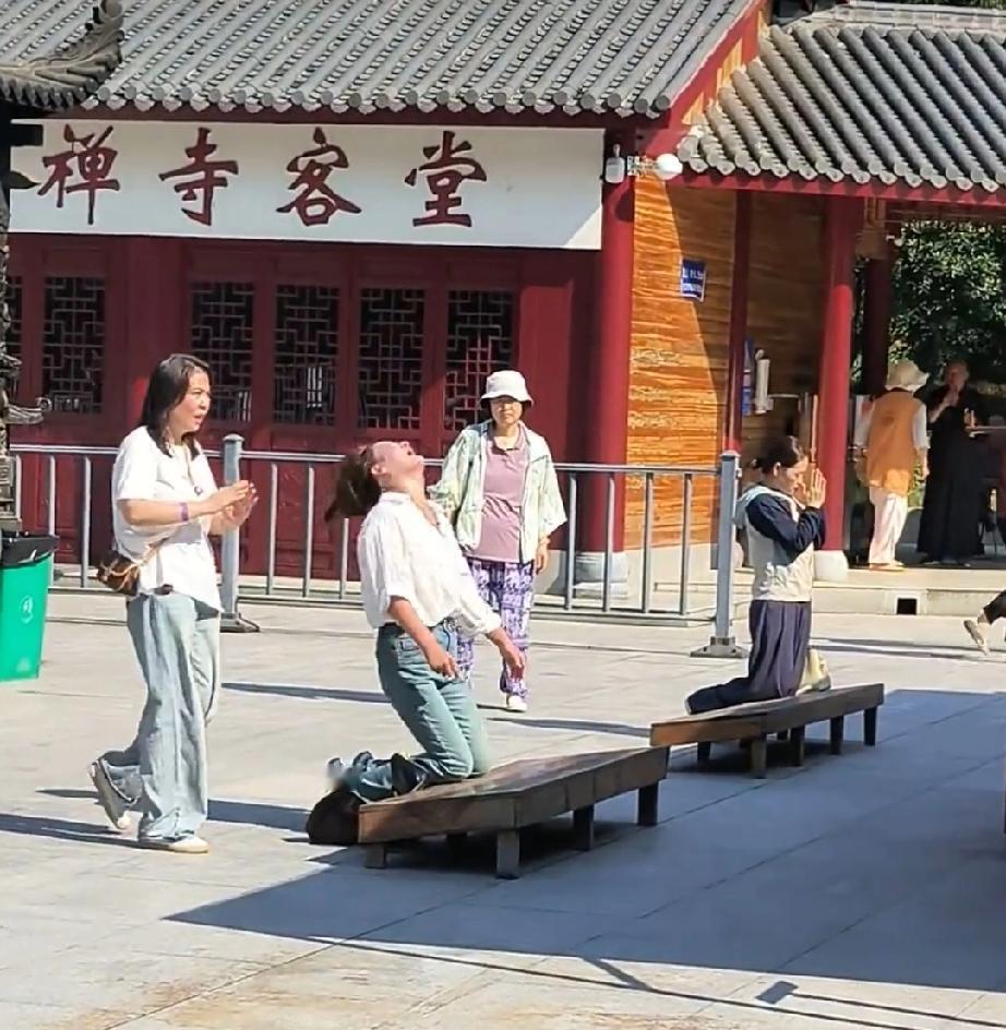 安徽九华山。女子情绪激动用头撞拜垫撞的咚咚响，边上女子拉都拉不住，那下面的拜垫可