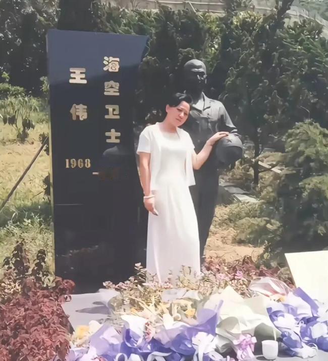 这是王伟烈士遗孀阮国琴，为丈夫扫墓时的照片，照片中，阮国琴站在王伟雕塑身旁，她的