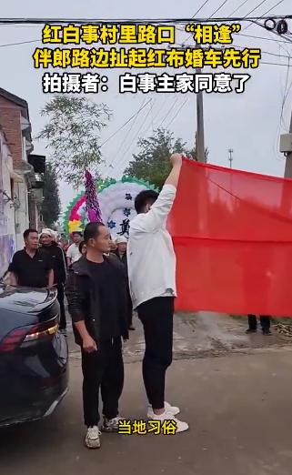 农村路口，婚车队伍和白事队伍意外遇上，场面看着就很微妙。按照当地的做法，伴郎在