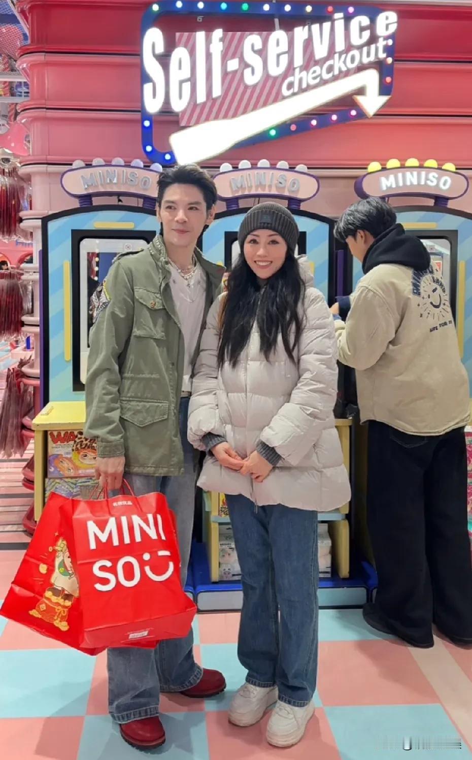 向佐在上海名优创品逛街，穿着一件绿色的长风衣，蓝色牛仔裤，脖子上带着珍珠项链，个