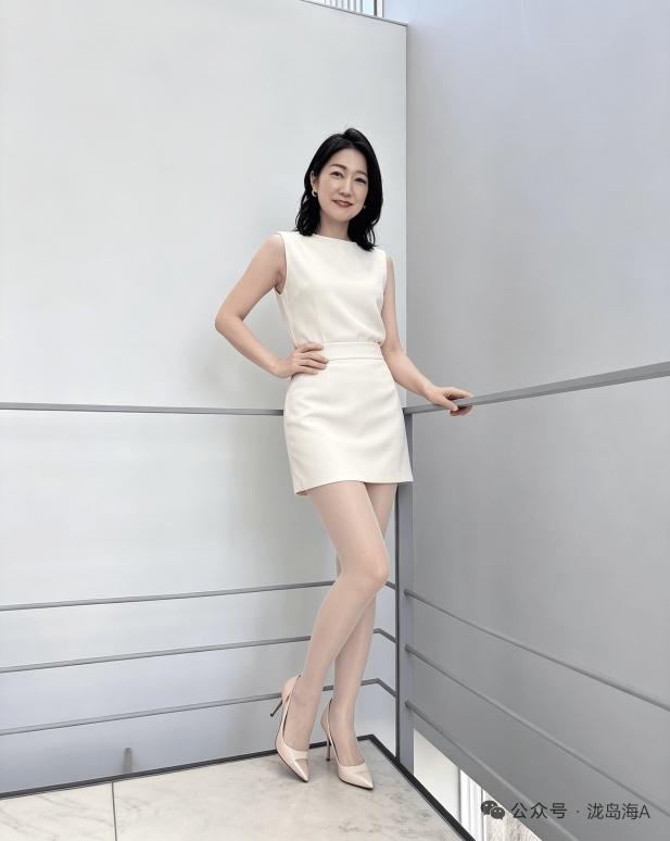 这姑娘穿着白裙，站在楼梯旁。